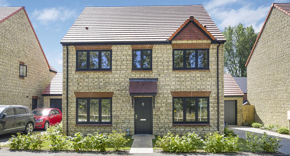 Detached stone home at Temple Gate with dark grey windows and front door