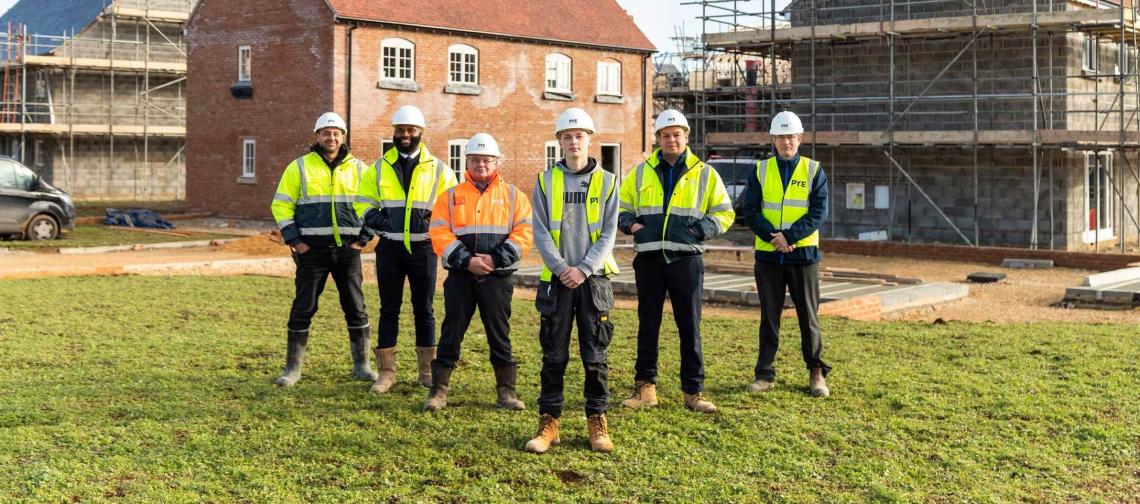 Six Pye Homes apprentices and staff in hard hats and hi-vis on a building site