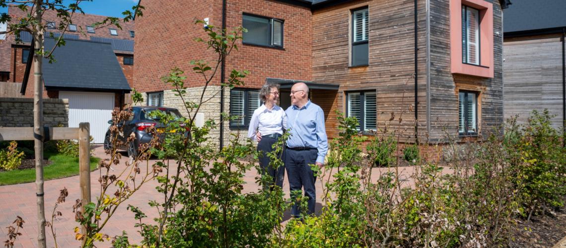 Couple standing in front of brick and timber-clad new homes at Church Farm
