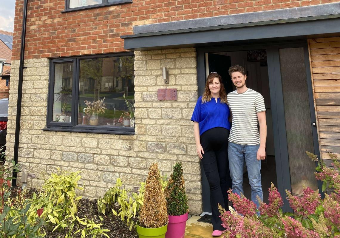 Couple standing in the doorway of their new stone and brick home at Church Farm