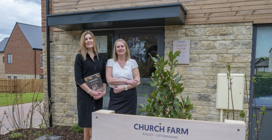 Two women outside the Church Farm customer lounge, one holding a brochure