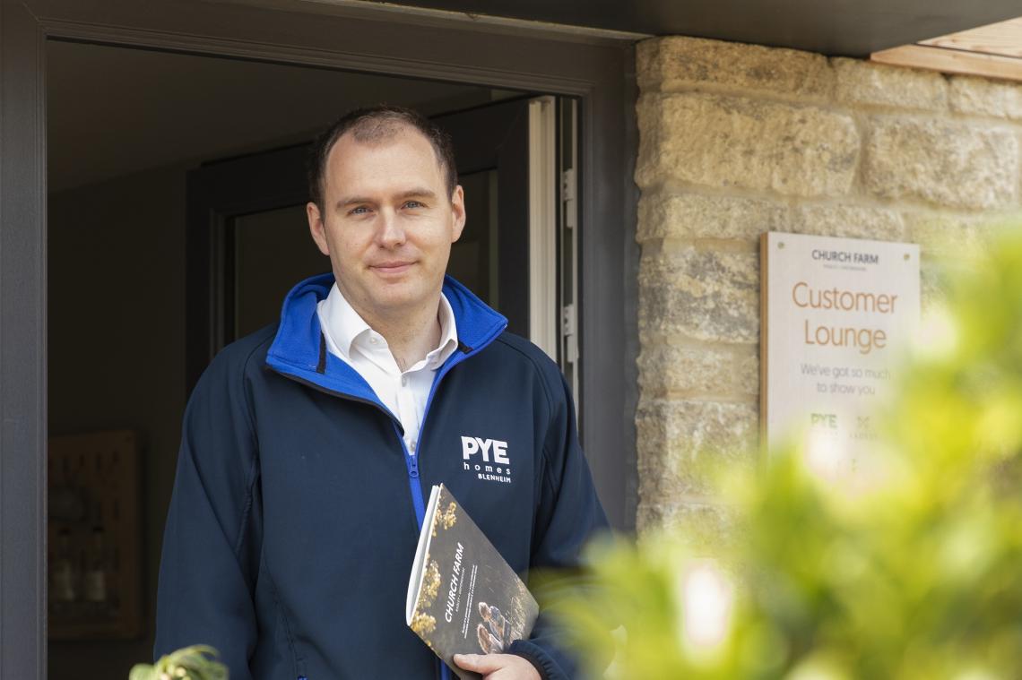 Mark Brooks holding a Church Farm brochure outside the Customer Lounge