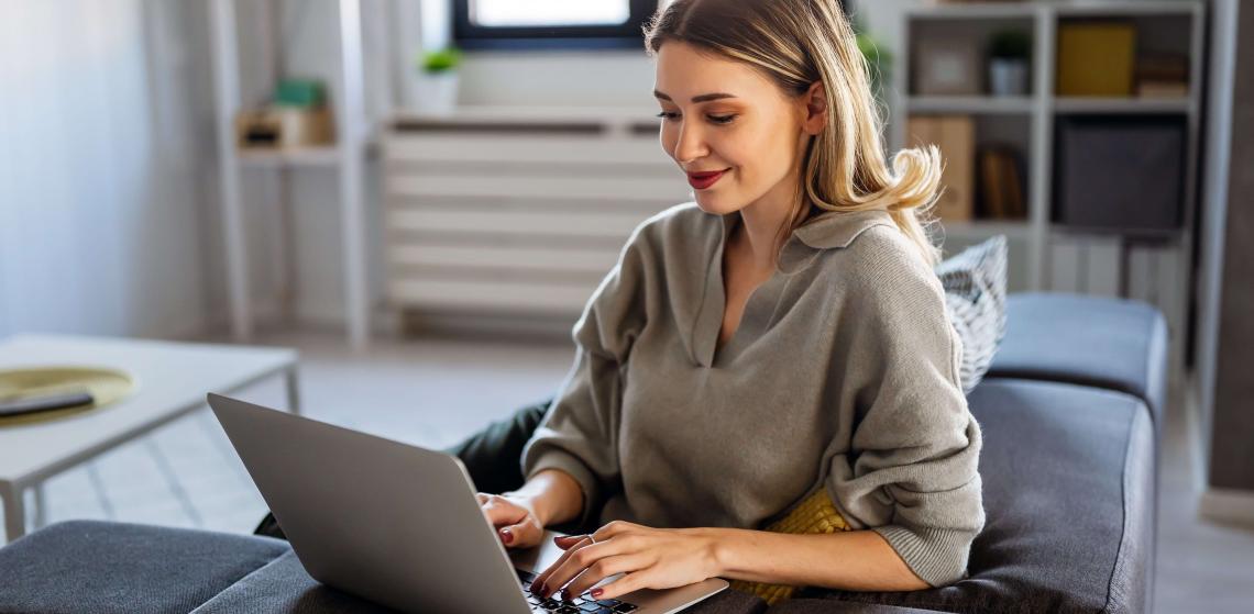 Woman using a laptop on a sofa at home