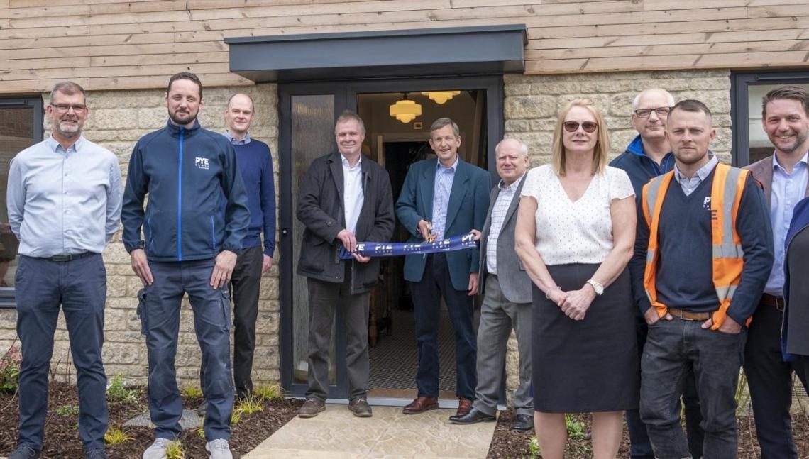 Pye Homes team at a ribbon-cutting outside a stone-fronted home