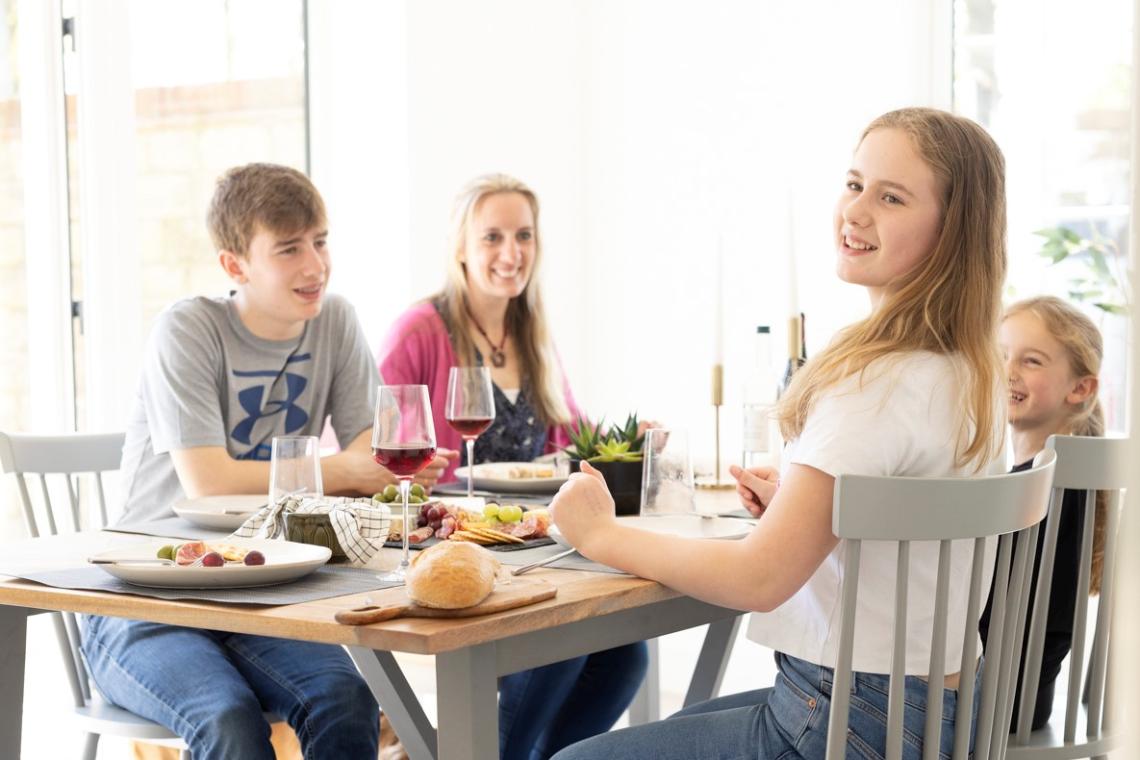 Family chatting around a dining table set with food and wine