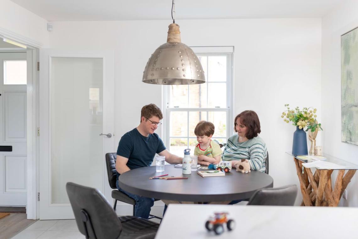 Family of three sitting at a round dining table in a bright kitchen